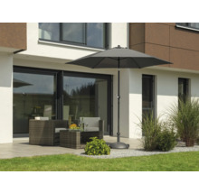 Gartenszene mit Sonnenschirm, Sitzgruppe und Bepflanzung vor einem Wohnhaus