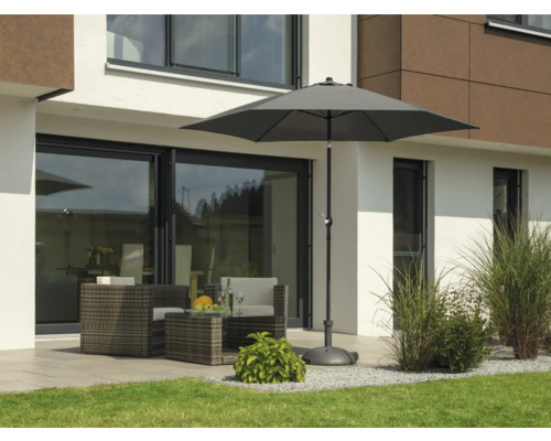 Gartenszene mit Sonnenschirm, Sitzgruppe und Bepflanzung vor einem Wohnhaus