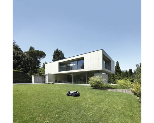 Rasenmähroboter auf Rasen vor modernem Haus