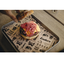 Ein Burger mit roter Zwiebel und Käse auf einem Tablett mit Papierunterlage.
