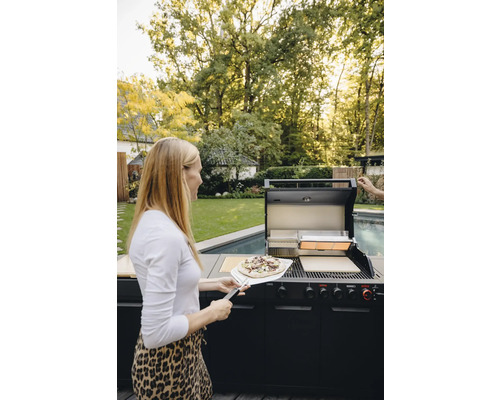 Frau mit Pizza vor einem Gasgrill im Freien