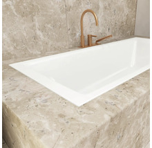 Detailaufnahme einer weißen Badewanne mit Armatur auf einer Marmoroberfläche.
