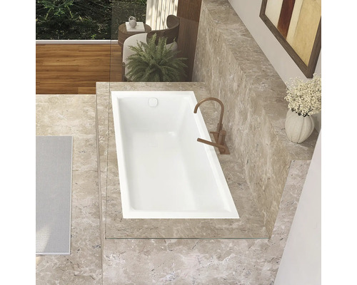 Draufsicht einer Badewanne in einem Badezimmer mit Marmorfliesen und Armatur.