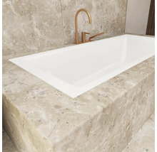 Detailansicht einer Einbaubadewanne mit Armatur und Marmorverkleidung.