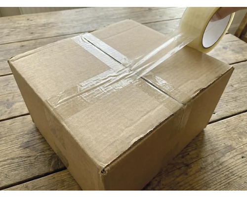 Ein Karton wird mit einem transparenten Klebeband verschlossen.