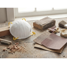 Staubmaske, Schleifpapier und Werkzeuge auf einer Werkbank