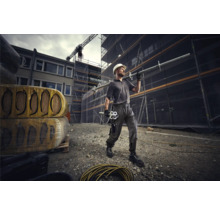 Bauarbeiter mit Schutzhelm und Gerüstbauteilen auf einer Baustelle.