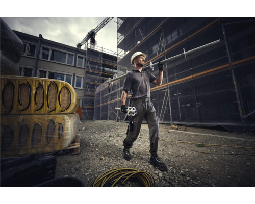 Bauarbeiter mit Schutzhelm und Gerüstbauteilen auf einer Baustelle.