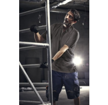 Mann in Arbeitskleidung auf einem Baugerüst