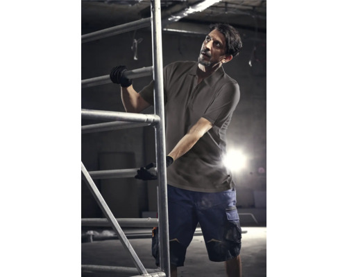 Mann in Arbeitskleidung auf einem Baugerüst