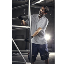 Mann auf einem Baugerüst in Arbeitskleidung mit Handschuhen