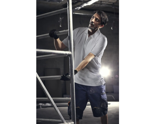 Mann auf einem Baugerüst in Arbeitskleidung mit Handschuhen