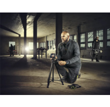 Mann mit Nivelliergerät auf Baustelle zur Messung