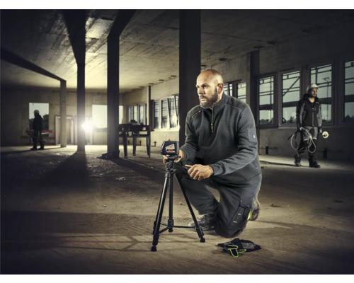 Mann mit Nivelliergerät auf Baustelle zur Messung