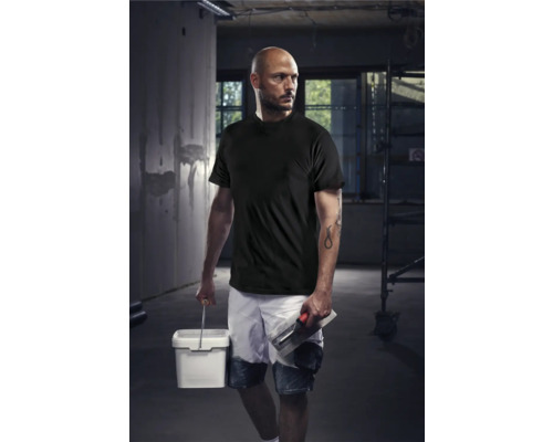 Mann in Arbeitskleidung mit Farbeimer und Maurerkelle auf einer Baustelle