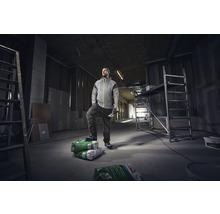 Handwerker steht in einer Baustelle mit Leiter und Gerüst