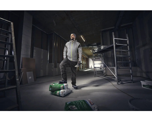 Handwerker steht in einer Baustelle mit Leiter und Gerüst