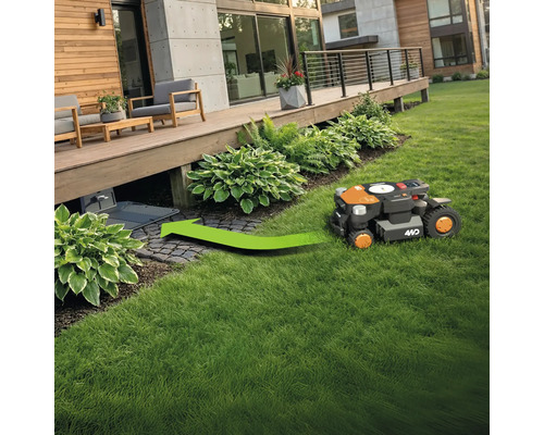 Ein Rasenmähroboter fährt auf einer Rasenfläche in Richtung Ladestation.