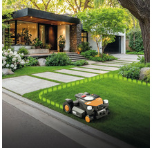 Rasenmähroboter im Einsatz vor modernem Wohnhaus mit gepflegtem Garten