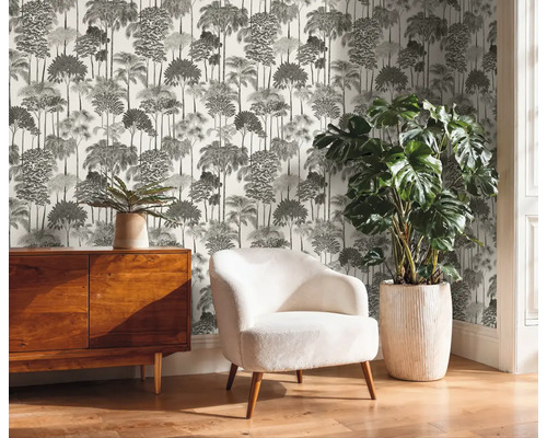 Raumansicht mit Kommode, Sessel, Zimmerpflanze und bedruckter Tapete mit Baummuster