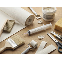 Werkzeuge und Materialien für Tapezierarbeiten auf einem Tisch