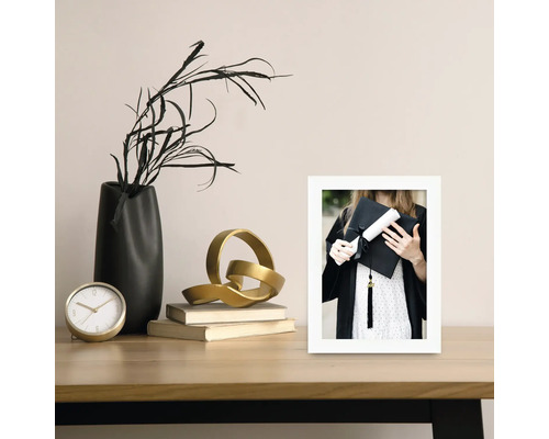 Dekoratives Stillleben mit Uhr, Vase, Skulptur, Büchern und einem gerahmten Foto