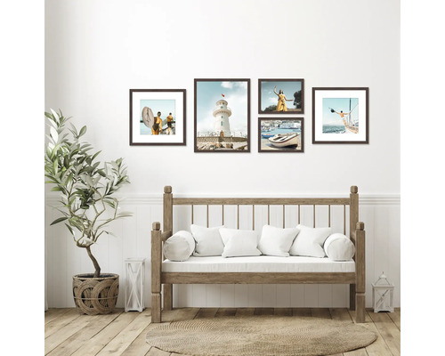 Dekorative Wand mit mehreren gerahmten Bildern über einer Holzbank mit Kissen