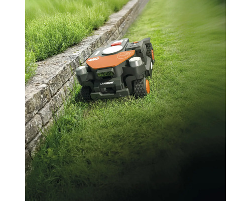 Landroid Mähroboter auf Rasen neben einer Mauer