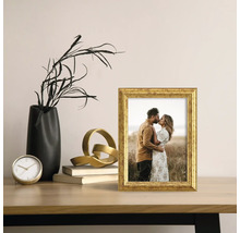 Dekorative Szene mit einem goldenen Bilderrahmen, einer schwarzen Vase und einer goldenen Skulptur