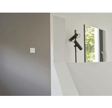 Innenaufnahme eines Raumes mit einer schwarzen Stehlampe, einem Fenster und einem Lichtschalter