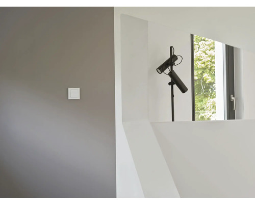 Innenaufnahme eines Raumes mit einer schwarzen Stehlampe, einem Fenster und einem Lichtschalter