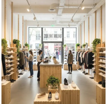Innenansicht eines Bekleidungsgeschäfts mit Kundschaft und einer Auswahl an Schuhen und Bekleidung