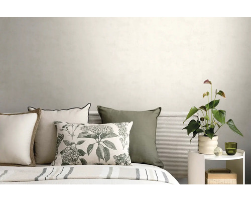 Bett mit Dekokissen, geripptem Kopfteil und weißem Beistelltisch mit Pflanze vor einer hellen Wand in einem modernen Schlafzimmer.