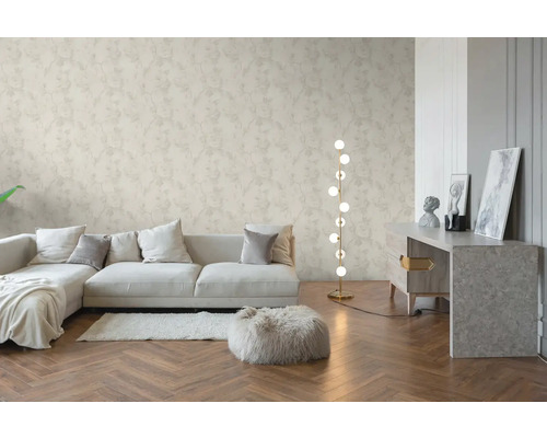 Helles Wohnzimmer mit floral gemusterter Vliestapete, Holzparkett im Fischgrätmuster, modernem Sofa und einer Stehlampe.