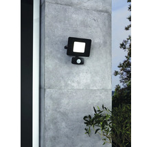 Schwarzer LED-Außenstrahler mit Bewegungsmelder an einer Wand montiert.