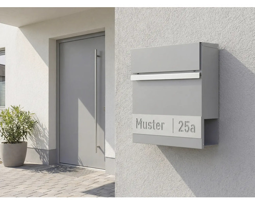 Grauer Briefkasten mit Zeitungsfach an einer Hauswand neben einer Tür