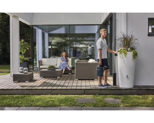 Moderner Terrassenbereich mit grauen Polyrattan-Gartenmöbeln, einer weißen Regentonne mit integriertem Pflanzgefäß und zwei Personen.