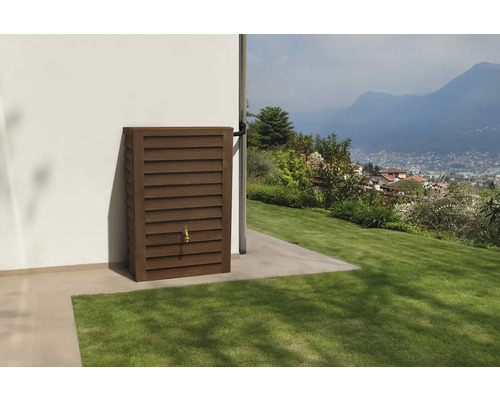 Rechteckiger Regenspeicher in Holzoptik mit Lamellen und Wasserhahn an einer Hauswand im Garten.