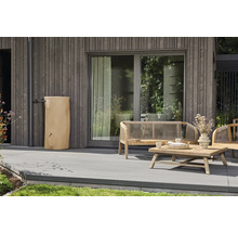 Beige Regentonne an einer grauen Holzfassade auf einer modernen Terrasse mit hölzernen Gartenmöbeln.