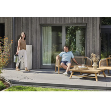 Moderne Holzterrasse mit Gartenmöbeln aus Holz, einer weißen Regentonne an der Hauswand und einer Person mit einer Gießkanne.
