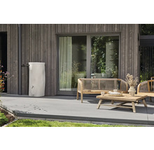 Weiße Regentonne an einer Holzfassade auf einer Terrasse mit Holzgartenmöbeln.