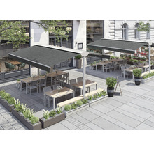 Terrasse mit Tischen, Stühlen und Markisen vor einem Gebäude