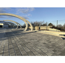 Gepflasterter Bereich mit Betonbögen im Freien.