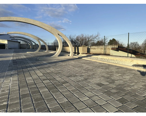 Gepflasterter Bereich mit Betonbögen im Freien.