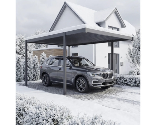 Ein Auto steht unter einem Carport vor einem Haus im Winter.