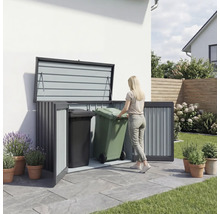Frau schiebt Mülltonne in eine Mülltonnenbox im Außenbereich