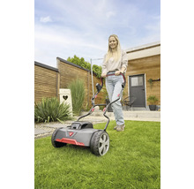 Eine Frau bedient einen Rasenmäher im Garten.