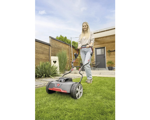 Eine Frau bedient einen Rasenmäher im Garten.