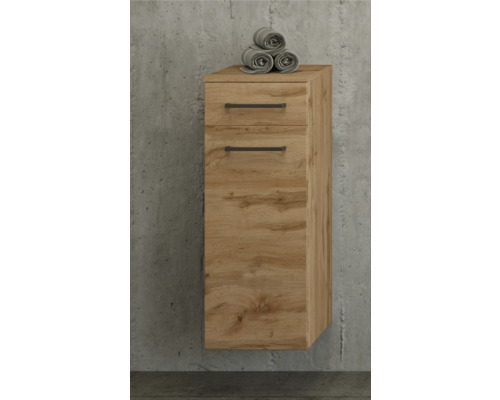 Wandhängender Badezimmerschrank in Eichenoptik mit einer Schublade, einer Tür und schwarzen Griffen vor einer Betonwand.