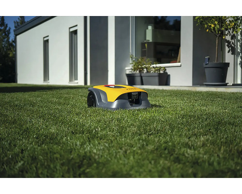 Gelber Mähroboter auf Rasen vor Haus